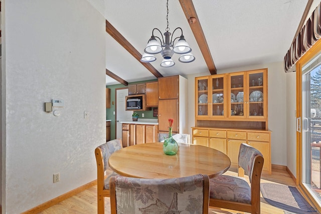 dining room with a chandelier, beam ceiling, and light hardwood / wood-style flooring