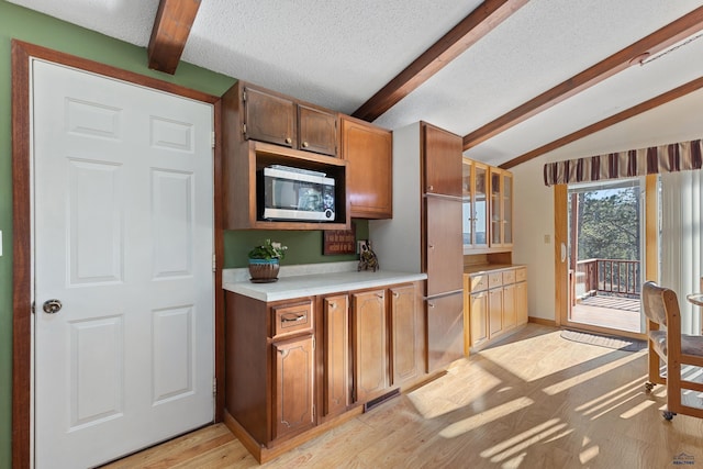 kitchen featuring lofted ceiling with beams, a textured ceiling, and light wood-type flooring