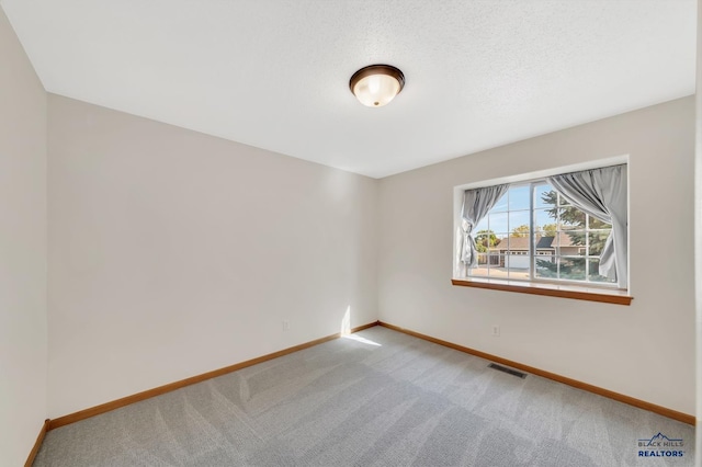 spare room featuring a textured ceiling and carpet