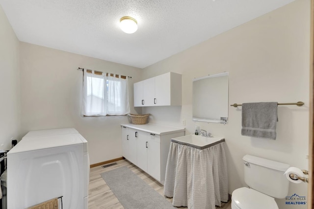 bathroom featuring sink, hardwood / wood-style flooring, washing machine and dryer, a textured ceiling, and toilet