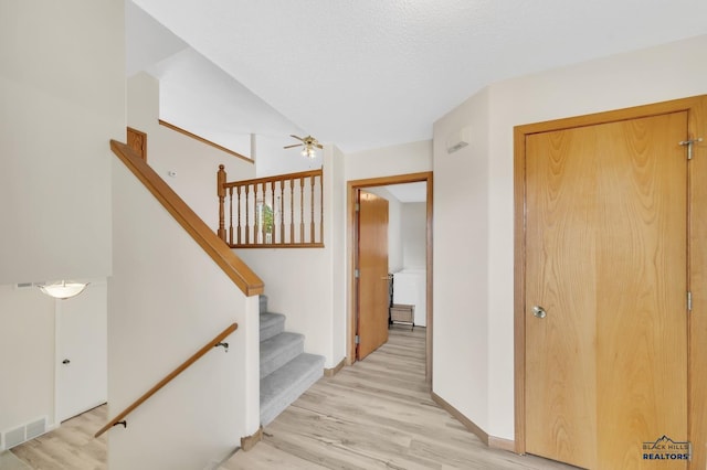 stairway featuring lofted ceiling, ceiling fan, hardwood / wood-style flooring, and a textured ceiling