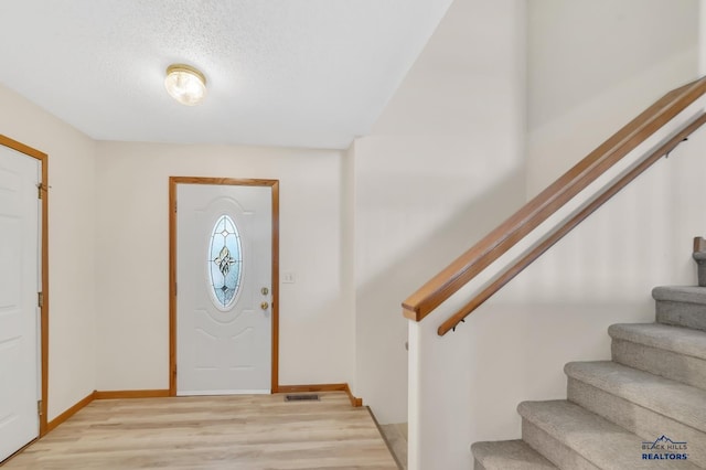 entryway with a textured ceiling and light hardwood / wood-style flooring