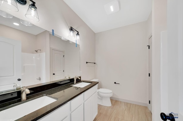 bathroom with a shower, hardwood / wood-style floors, vanity, and toilet