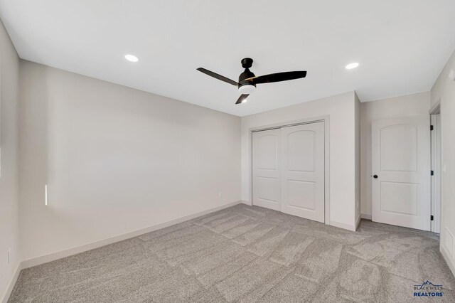 unfurnished bedroom with light colored carpet, a closet, and ceiling fan