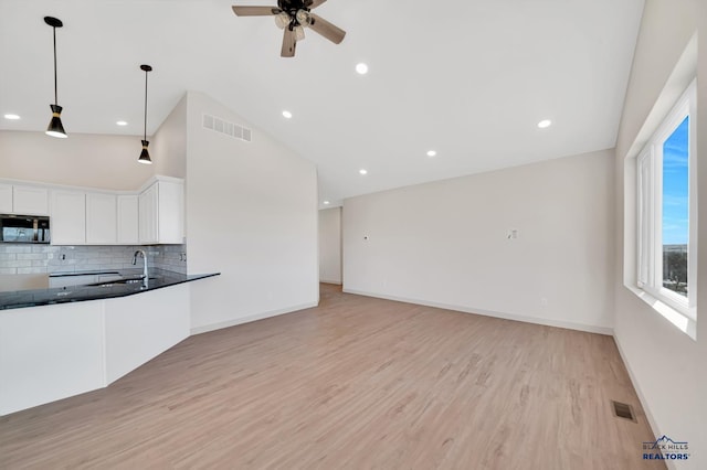 kitchen featuring sink, white cabinetry, tasteful backsplash, decorative light fixtures, and light hardwood / wood-style flooring