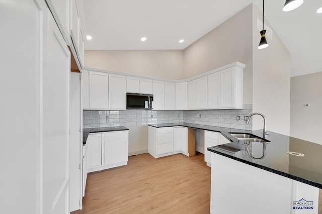 kitchen with sink, decorative light fixtures, light hardwood / wood-style flooring, white cabinets, and backsplash