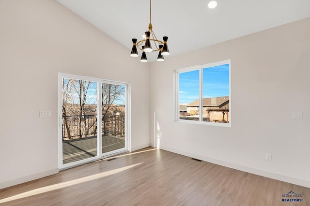 unfurnished dining area with wood-type flooring, a chandelier, and vaulted ceiling