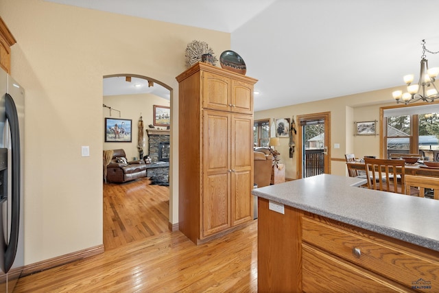 369 Deegan Dr, Hill City, SD 57745 - kitchen featuring pendant lighting, lofted ceiling, stainless steel fridge with ice dispenser, a stone fireplace, and light wood-type flooring