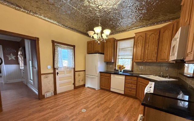 kitchen with sink, light hardwood / wood-style flooring, a notable chandelier, white appliances, and decorative backsplash