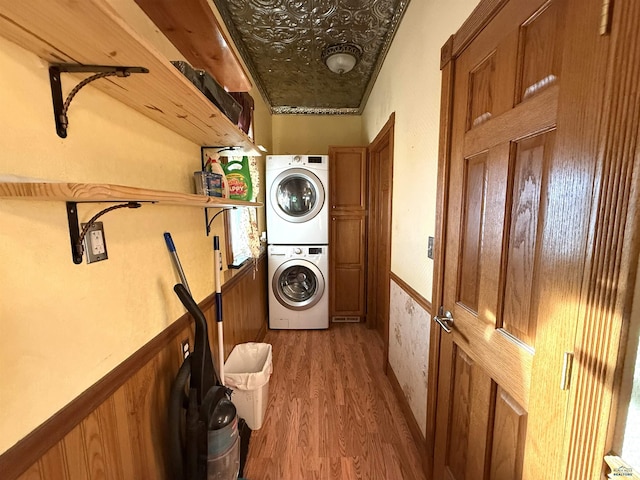 clothes washing area with wood-type flooring and stacked washer / drying machine