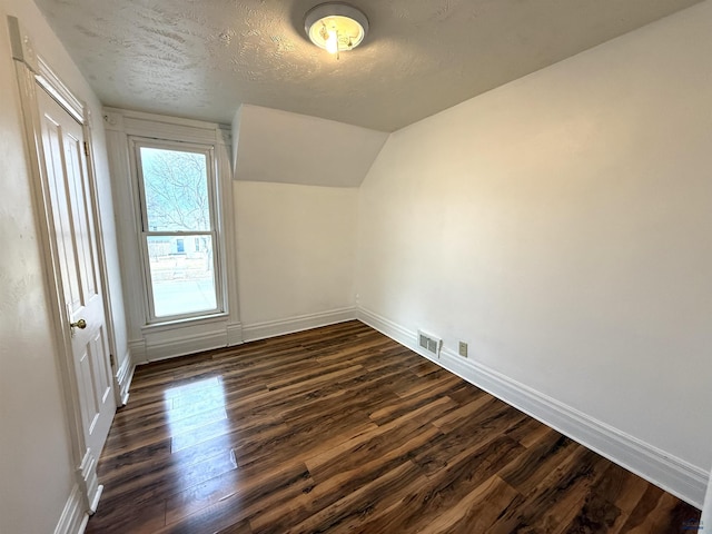 additional living space featuring lofted ceiling, a textured ceiling, and dark hardwood / wood-style flooring