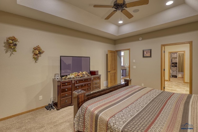 carpeted bedroom featuring ceiling fan and a raised ceiling