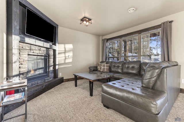 carpeted living area with a stone fireplace and baseboards