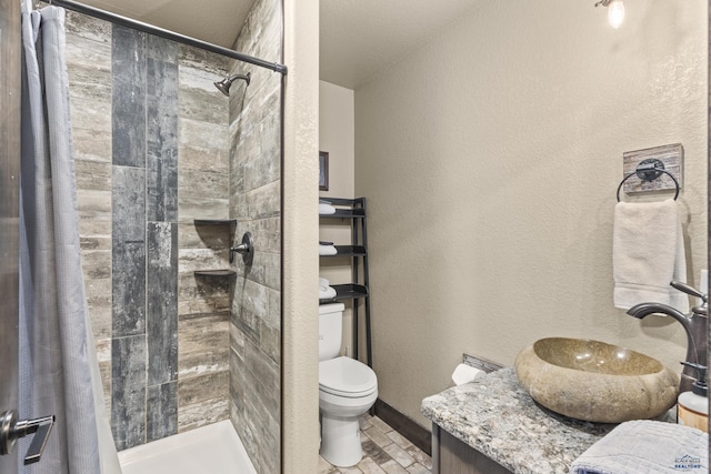 bathroom with a textured wall, a shower stall, toilet, and vanity