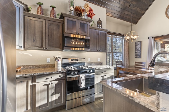 kitchen featuring dark stone countertops, sink, stainless steel appliances, and dark brown cabinetry