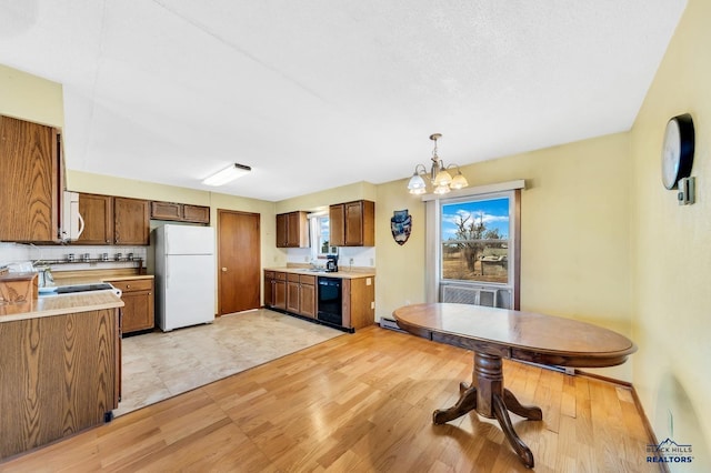 kitchen featuring pendant lighting, sink, backsplash, a chandelier, and white appliances