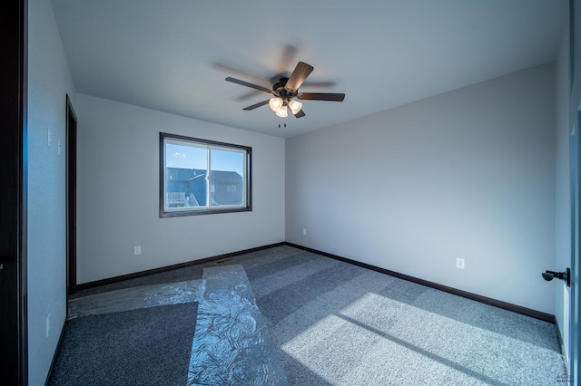 empty room with dark colored carpet and ceiling fan