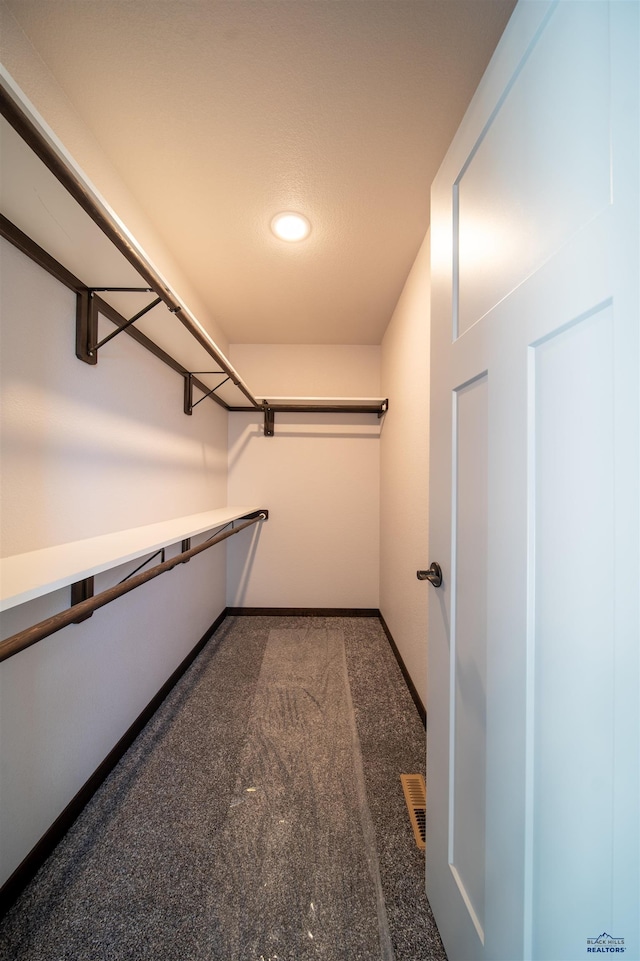 spacious closet featuring dark carpet