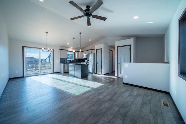 unfurnished living room featuring vaulted ceiling, ceiling fan with notable chandelier, and dark hardwood / wood-style flooring