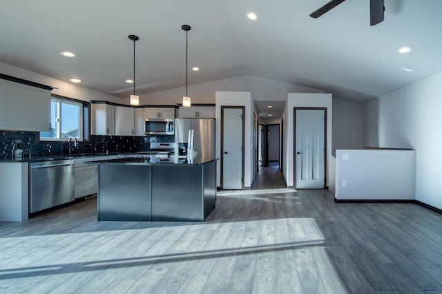 kitchen featuring vaulted ceiling, a kitchen island, pendant lighting, gray cabinetry, and stainless steel appliances