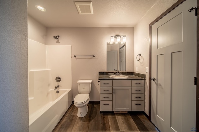 full bathroom featuring hardwood / wood-style flooring, vanity, washtub / shower combination, and toilet