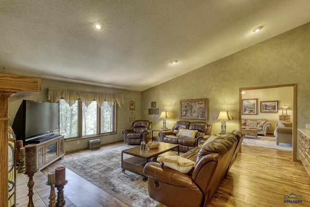 living room with vaulted ceiling, a textured ceiling, and light wood-type flooring