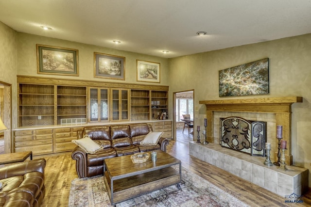 living room with hardwood / wood-style flooring, a towering ceiling, and a tile fireplace