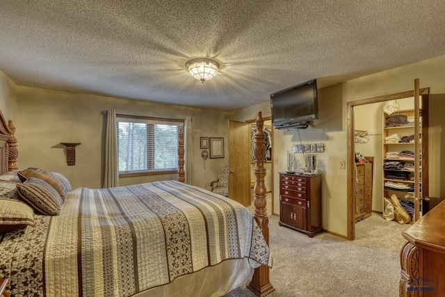 carpeted bedroom featuring a walk in closet, a closet, and a textured ceiling