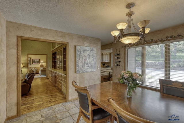 dining space with light tile patterned floors, a notable chandelier, and a textured ceiling