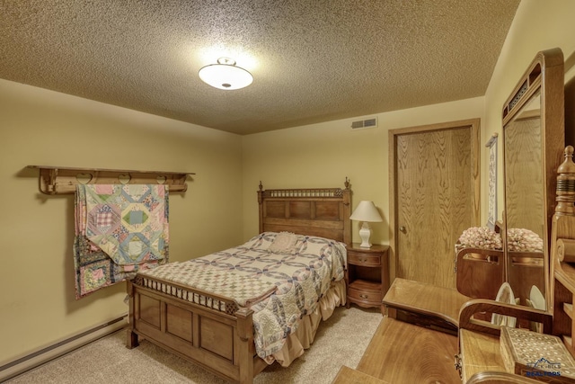 carpeted bedroom with a textured ceiling and a baseboard heating unit