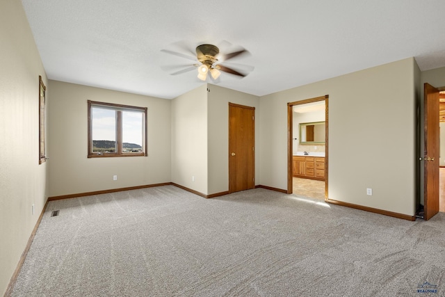 unfurnished bedroom featuring light carpet, connected bathroom, and ceiling fan