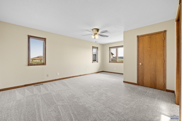 carpeted spare room featuring a textured ceiling and ceiling fan