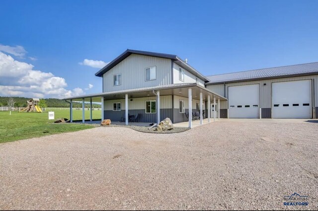 farmhouse with a playground, a garage, a porch, and a front yard