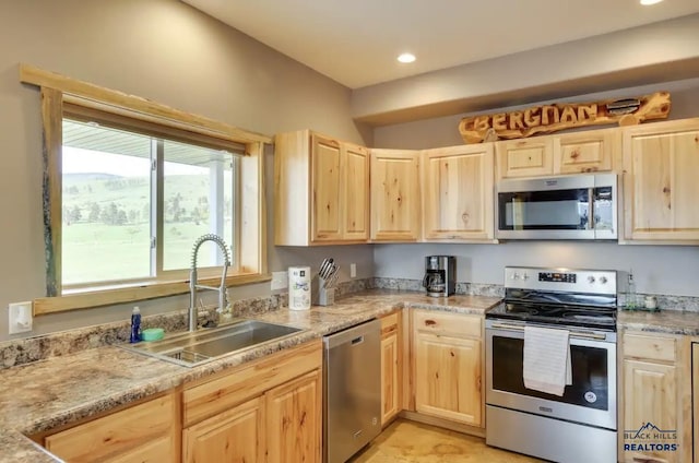 kitchen featuring appliances with stainless steel finishes, sink, light brown cabinets, and light stone counters