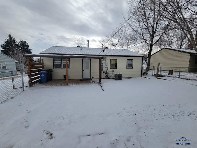 snow covered back of property with central AC