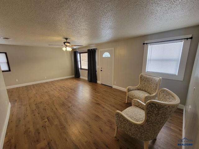 sitting room with ceiling fan, wood-type flooring, and a textured ceiling