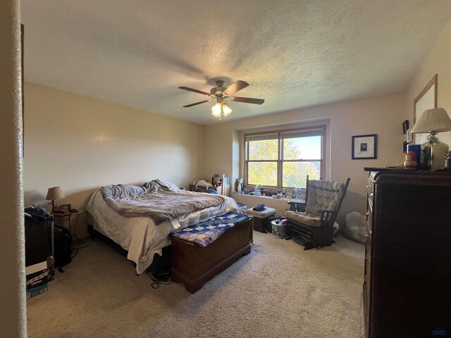 carpeted bedroom featuring ceiling fan and a textured ceiling