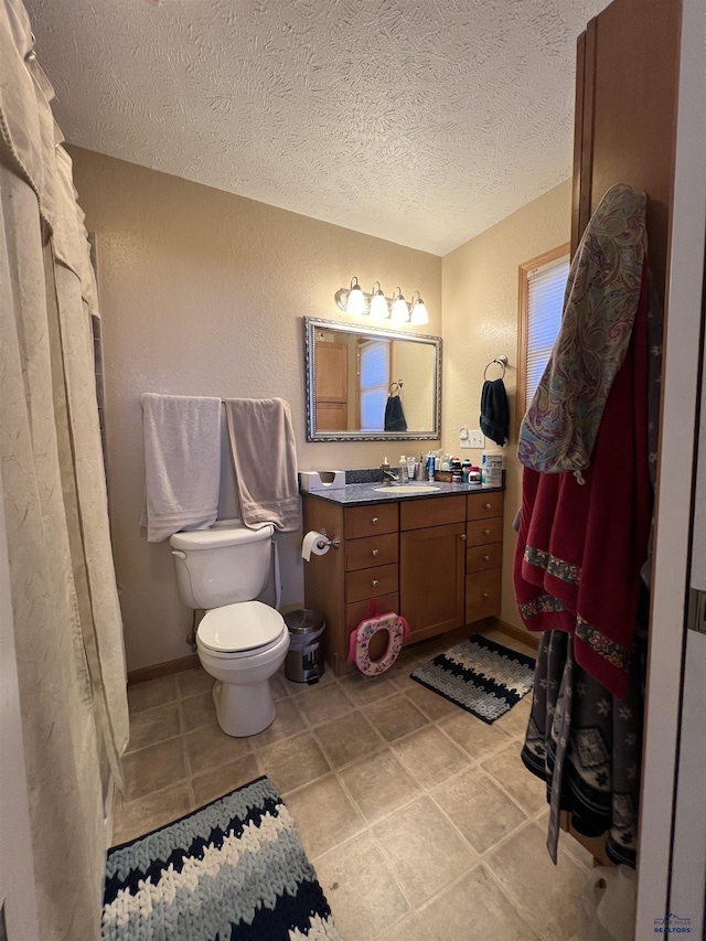 bathroom featuring vanity, a textured ceiling, and toilet