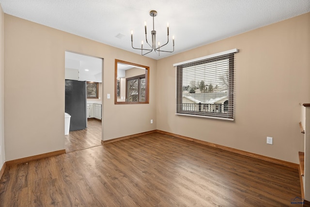 unfurnished dining area featuring hardwood / wood-style flooring and a chandelier