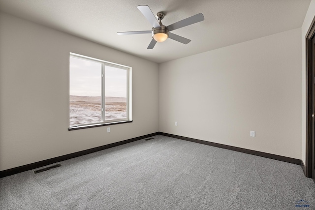 carpeted spare room featuring ceiling fan and a textured ceiling