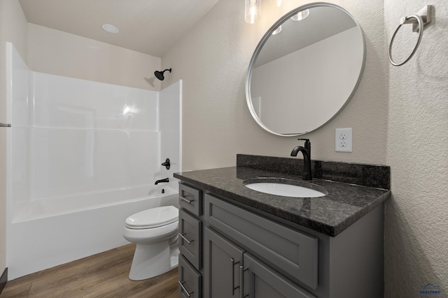 full bathroom with hardwood / wood-style flooring, vanity, shower / bathing tub combination, and toilet