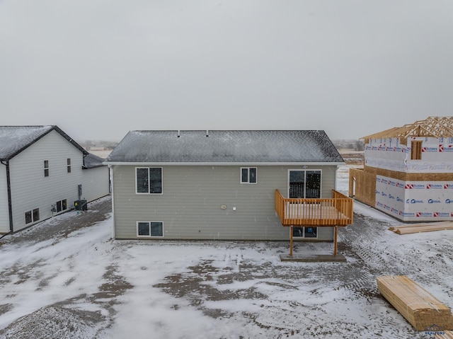 snow covered rear of property with a wooden deck