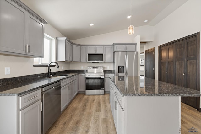 kitchen with lofted ceiling, sink, a center island, and appliances with stainless steel finishes