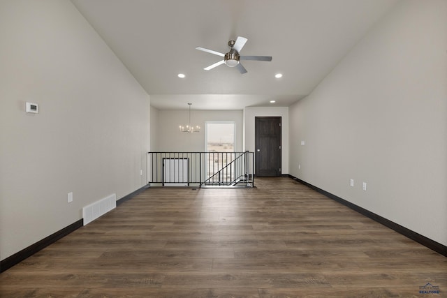 spare room featuring dark wood-type flooring and ceiling fan with notable chandelier