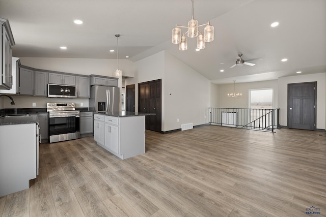 kitchen with gray cabinetry, decorative light fixtures, a center island, light wood-type flooring, and appliances with stainless steel finishes