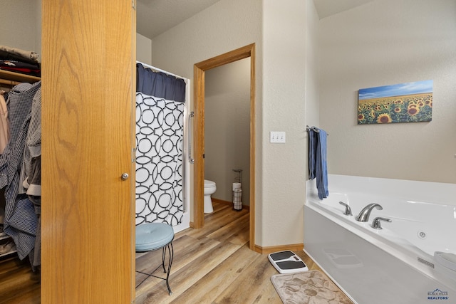 bathroom with hardwood / wood-style flooring, a washtub, and toilet