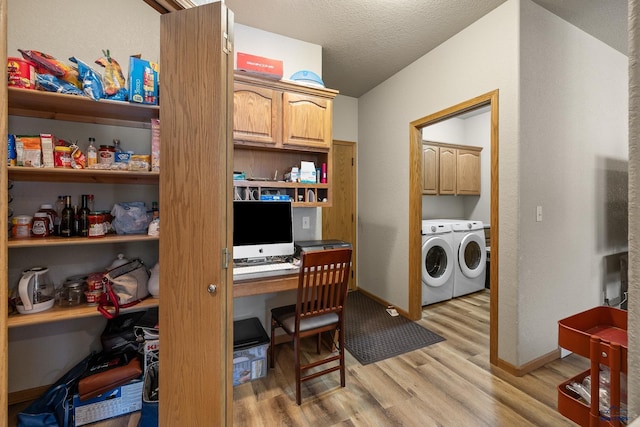 laundry room featuring a textured ceiling, light hardwood / wood-style floors, cabinets, and washing machine and clothes dryer