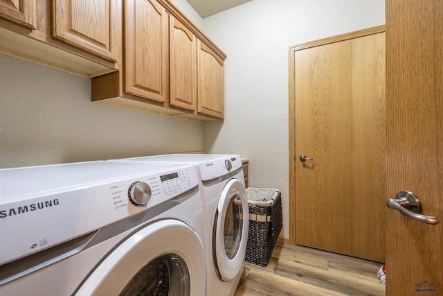 laundry room with separate washer and dryer, cabinets, and light wood-type flooring