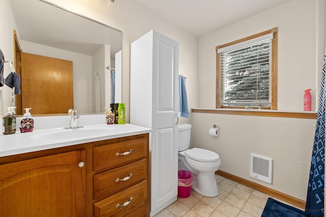 bathroom with vanity, heating unit, and toilet