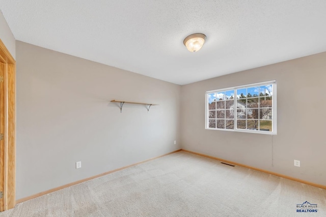 carpeted empty room featuring a textured ceiling